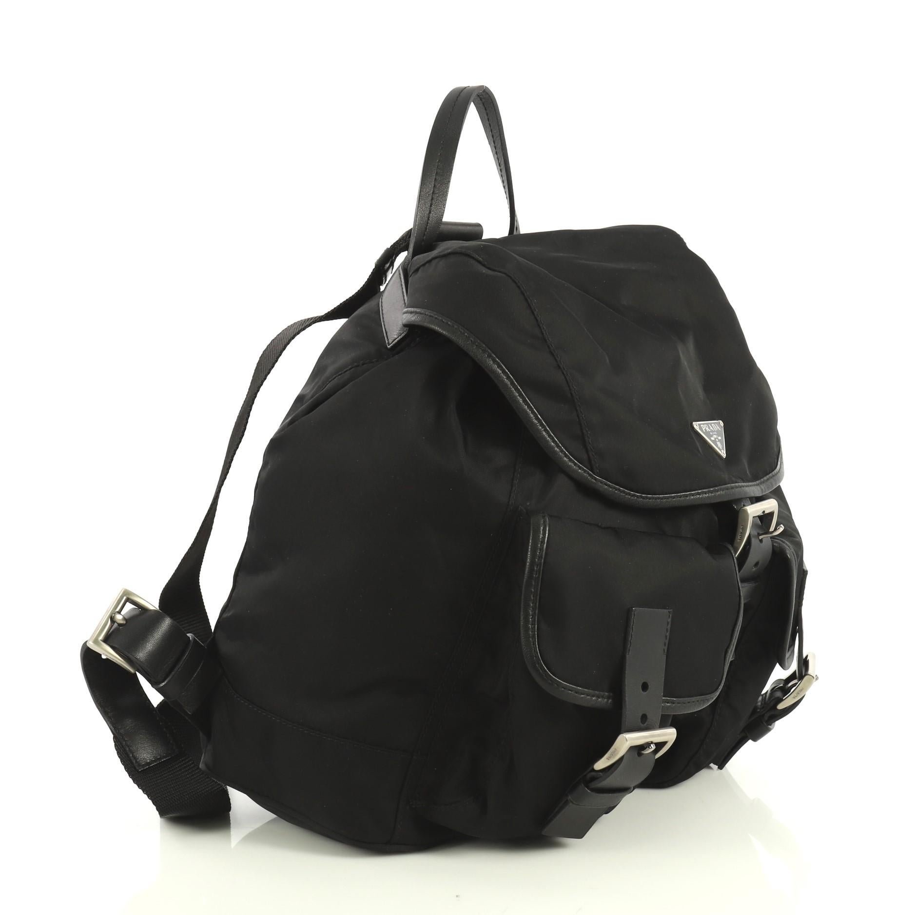 This Prada Double Front Pocket Backpack Tessuto Medium, crafted in black tessuto nylon, features a top carry handle, adjustable shoulder straps, top flap with buckle closure, exterior front pockets, and silver-tone hardware. Its drawstring closure
