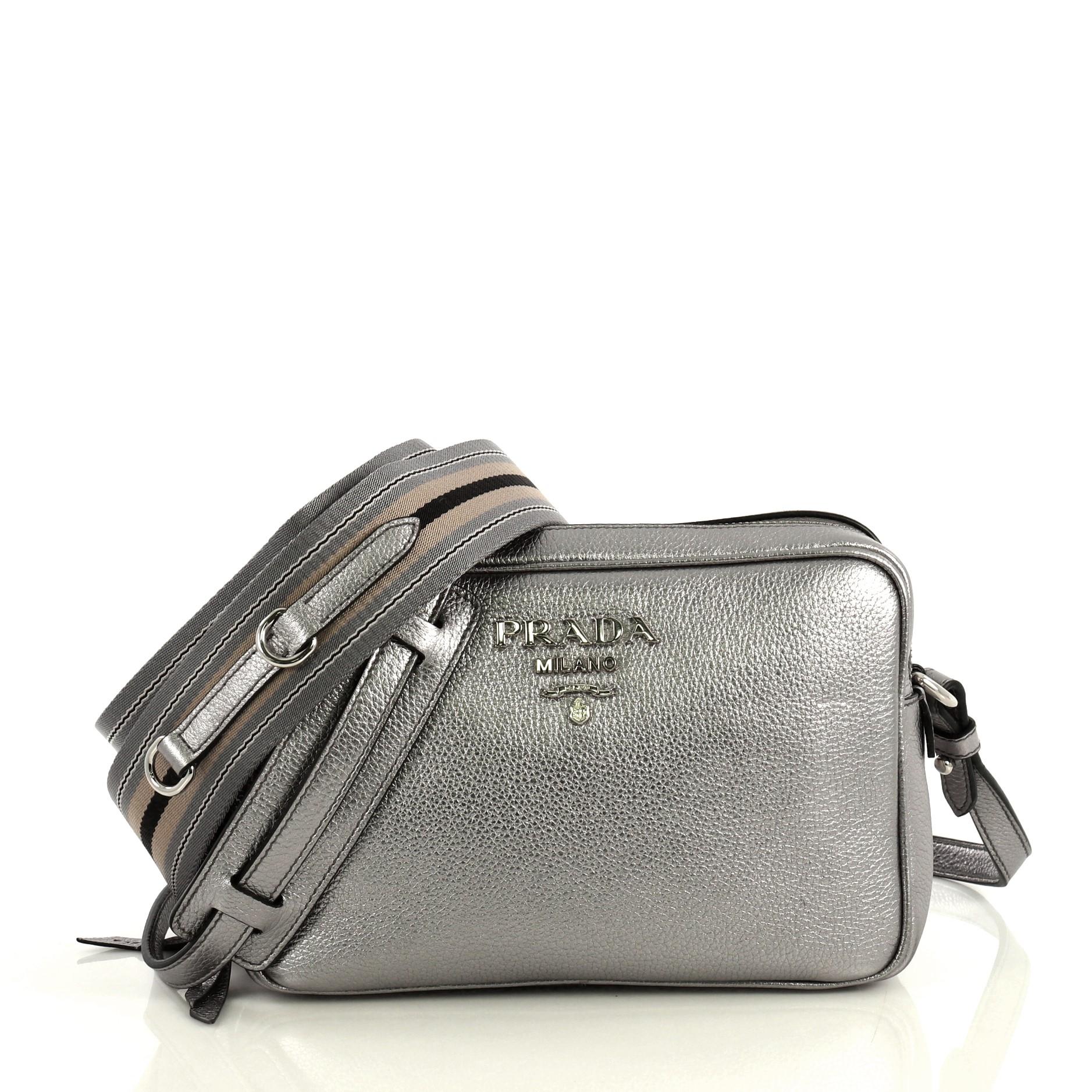 This Prada Double Zip Camera Bag Vitello Daino, crafted in silver vitello daino, features a detachable strap, Prada logo, and silver tone hardware. Its dual compartment with zip closure opens to a black fabric interior. 

Estimated Retail Price: