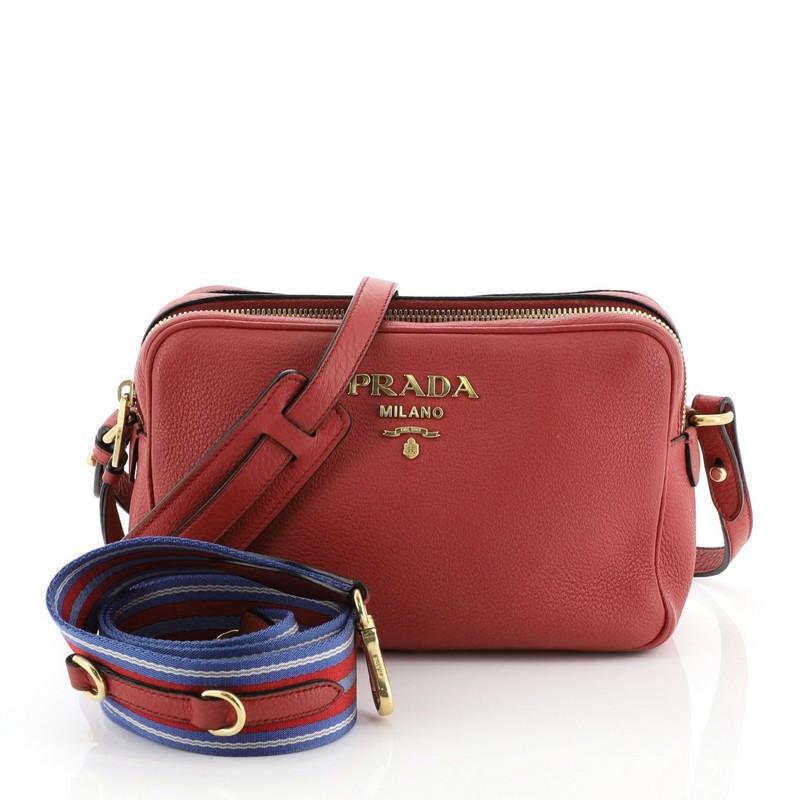 This Prada Double Zip Camera Bag Vitello Daino, crafted in red vitello daino leather, features an adjustable strap, Prada logo, and gold-tone hardware. Its dual compartment with zip closure opens to a black fabric interior. 

Condition: Very good.