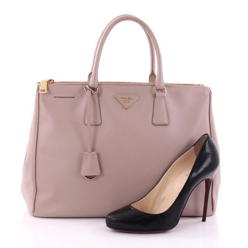 This authentic Prada Double Zip Lux Tote Saffiano Leather Large is the perfect bag to complete any outfit. Crafted from light pink saffiano leather, this boxy tote features side snap buttons, raised Prada logo, dual-rolled leather handles and