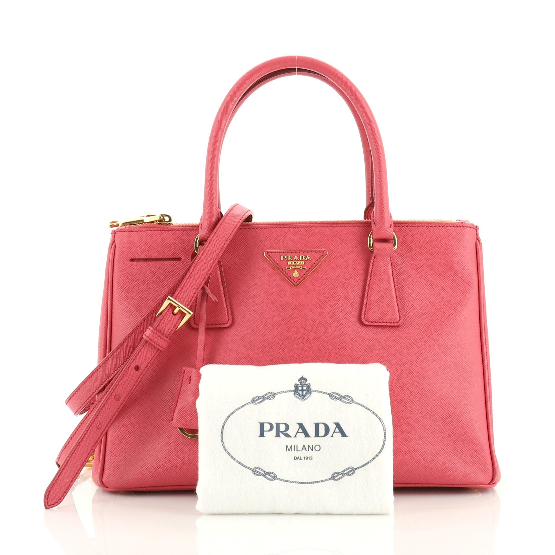 This Prada Double Zip Lux Tote Saffiano Leather Medium, crafted from pink saffiano leather, features dual rolled handles, raised Prada logo plate, and gold-tone hardware. It opens to a pink fabric and leather interior with two zip compartments on