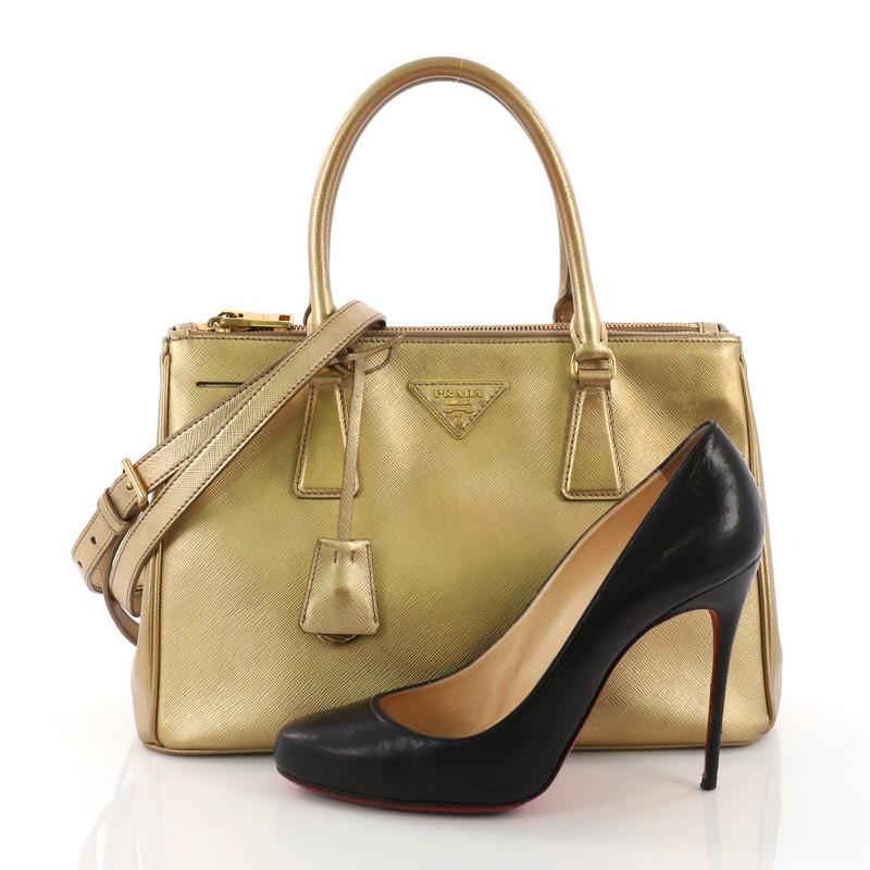 This Prada Double Zip Lux Tote Saffiano Leather Small, crafted from gold saffiano leather, features dual rolled handles, raised Prada logo plate, and gold-tone hardware. It opens to a gold fabric interior with two zip compartments on both sides and