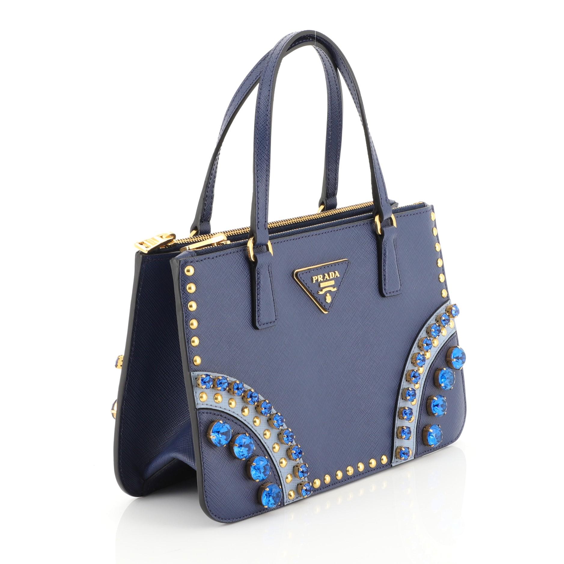 This Prada Double Zip Tote Crystal Embellished Saffiano Leather Mini, crafted from blue embellished saffiano leather, features dual rolled leather handles, raised Prada plate and gold-tone hardware. It opens to a black leather interior with two zip