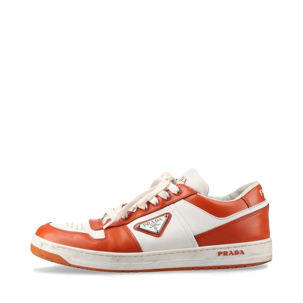 La basket en cuir Downtown de Prada, en marron et blanc, allie un design contemporain à un savoir-faire luxueux. Fabriquée en cuir de première qualité, cette basket présente une silhouette basse élégante avec une tige marron riche contrastée par des