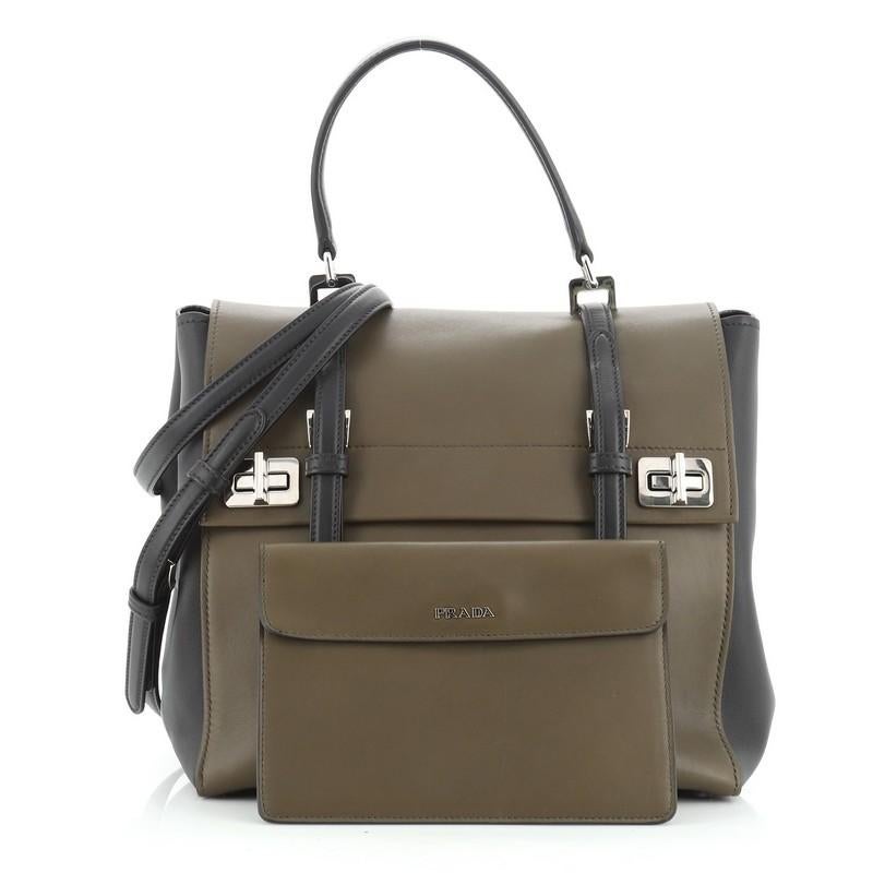 This Prada Dual Flap Double Turn Lock Satchel City Calfskin Medium, crafted in black and green city calfskin, features top handle with rings, dual-sided flap compartments, front turn-lock closures, magnetic back with logo lettering, and silver-tone