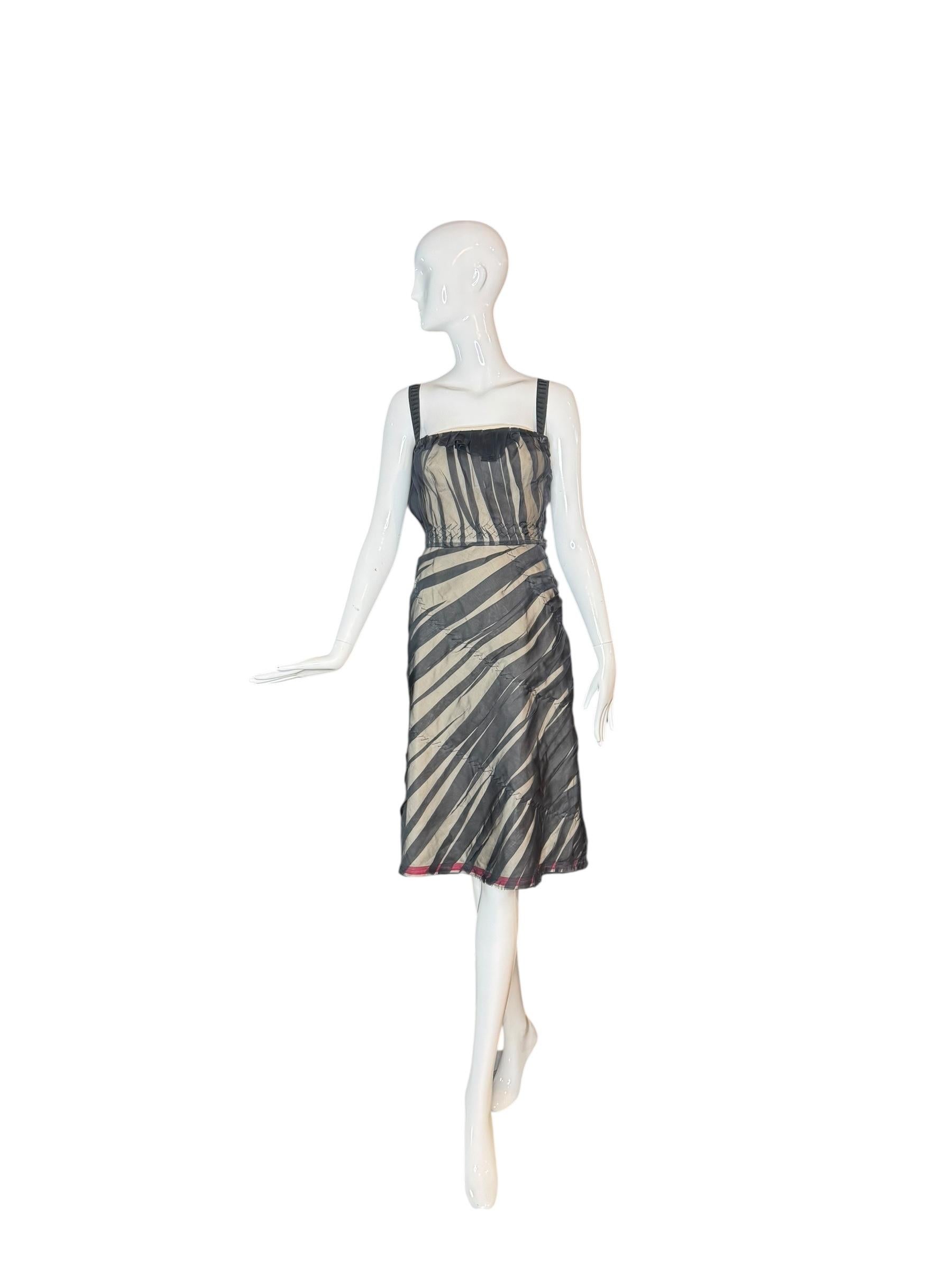 Questo abito Prada dei primi anni 2000 incarna l'approccio decostruito di Miuccia Prada alla femminilità moderna, dove la costruzione couture incontra la sovversione intellettuale. Realizzato in organza di seta a righe trasparenti stratificate su