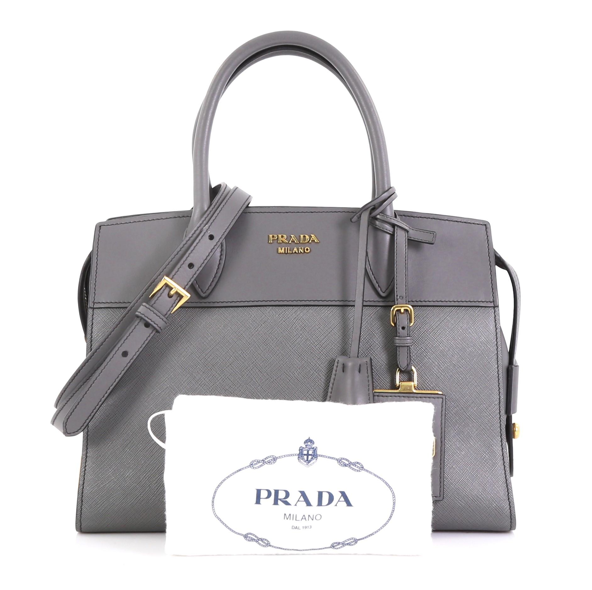 This Prada Esplanade Bag Saffiano Leather Medium, crafted from gray saffiano leather, features dual rolled leather handles, signature Prada logo at top center, and gold-tone hardware. Its zip closure opens to a black fabric interior with zip and