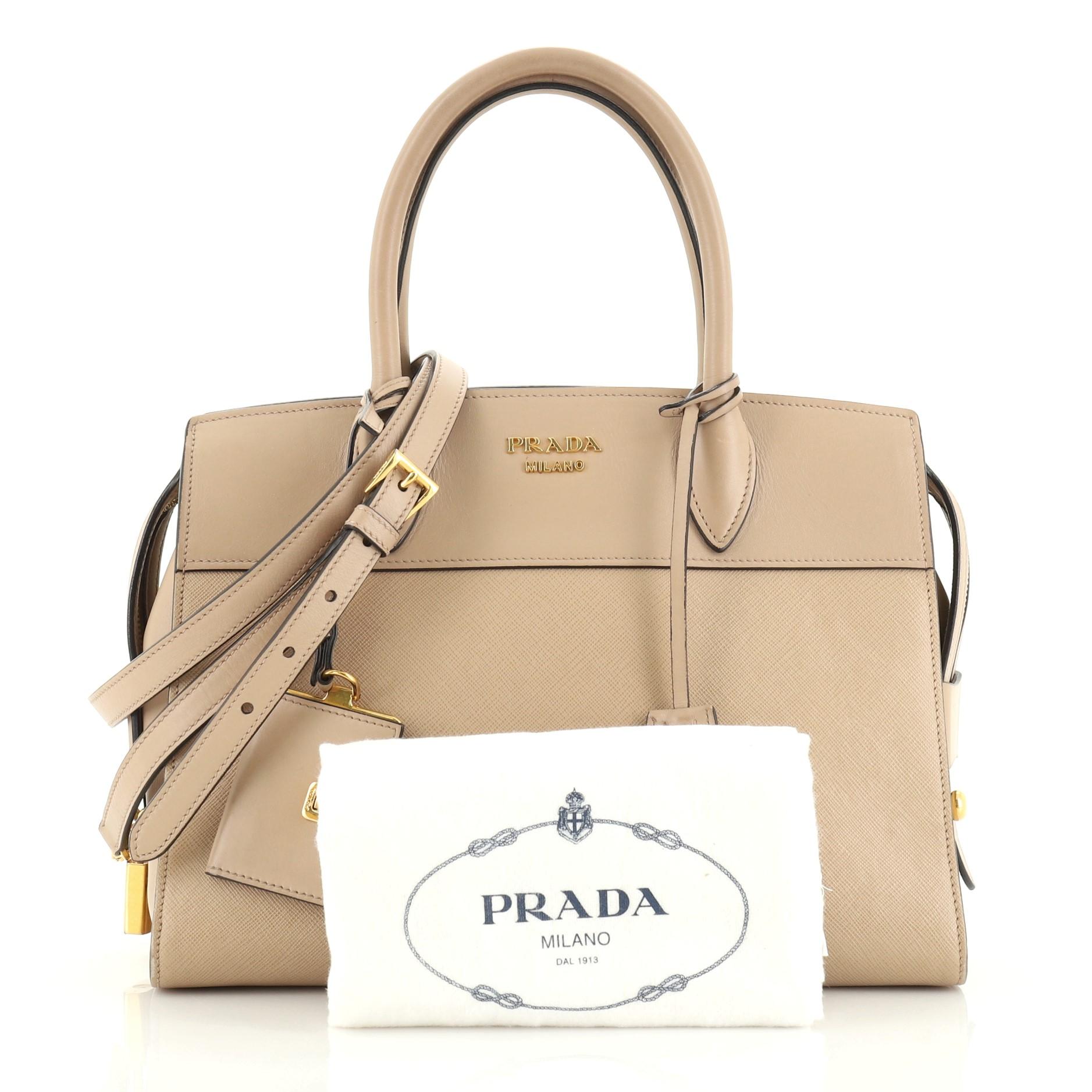 This Prada Esplanade Bag Saffiano Leather Medium, crafted in neutral saffiano leather, features dual rolled leather handles, Prada metal logo at center and gold-tone hardware. Its zip closure opens to a black and neutral leather interior with zip