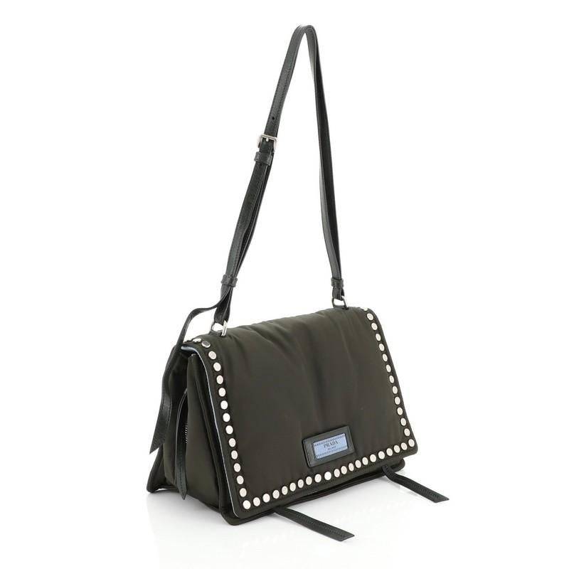 This Prada Etiquette Flap Bag Studded Tessuto Small, crafted from green nylon with disc studs, features a detachable shoulder strap, and aged silver-tone hardware. It opens to a blue nylon interior divided into two open compartments with a center