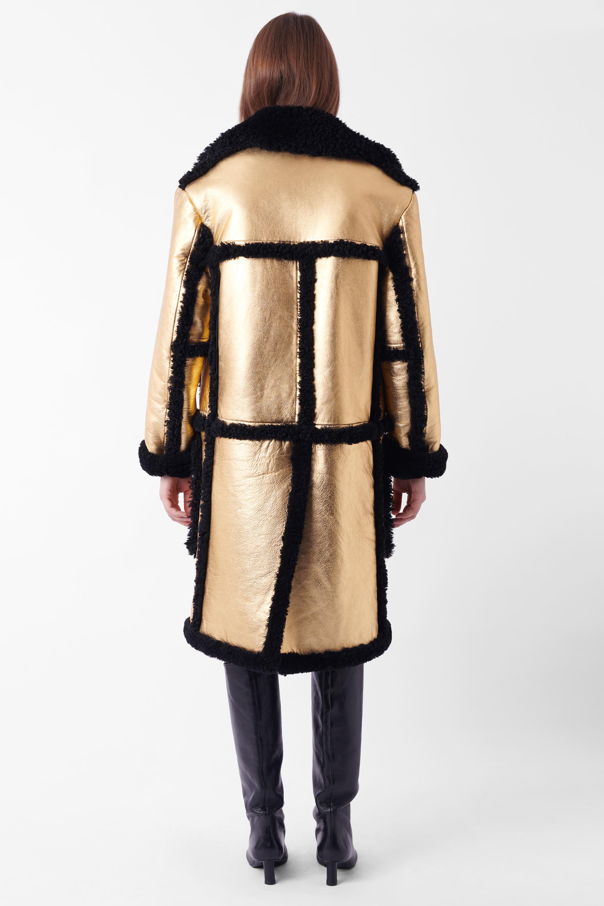 We are excited to present this beautiful Prada Fall Winter 2014 gold shearling coat. Features gold outer with inner black shearling lining, shearling accents, two deep front pockets and silver button closure. In excellent condition - brand new with