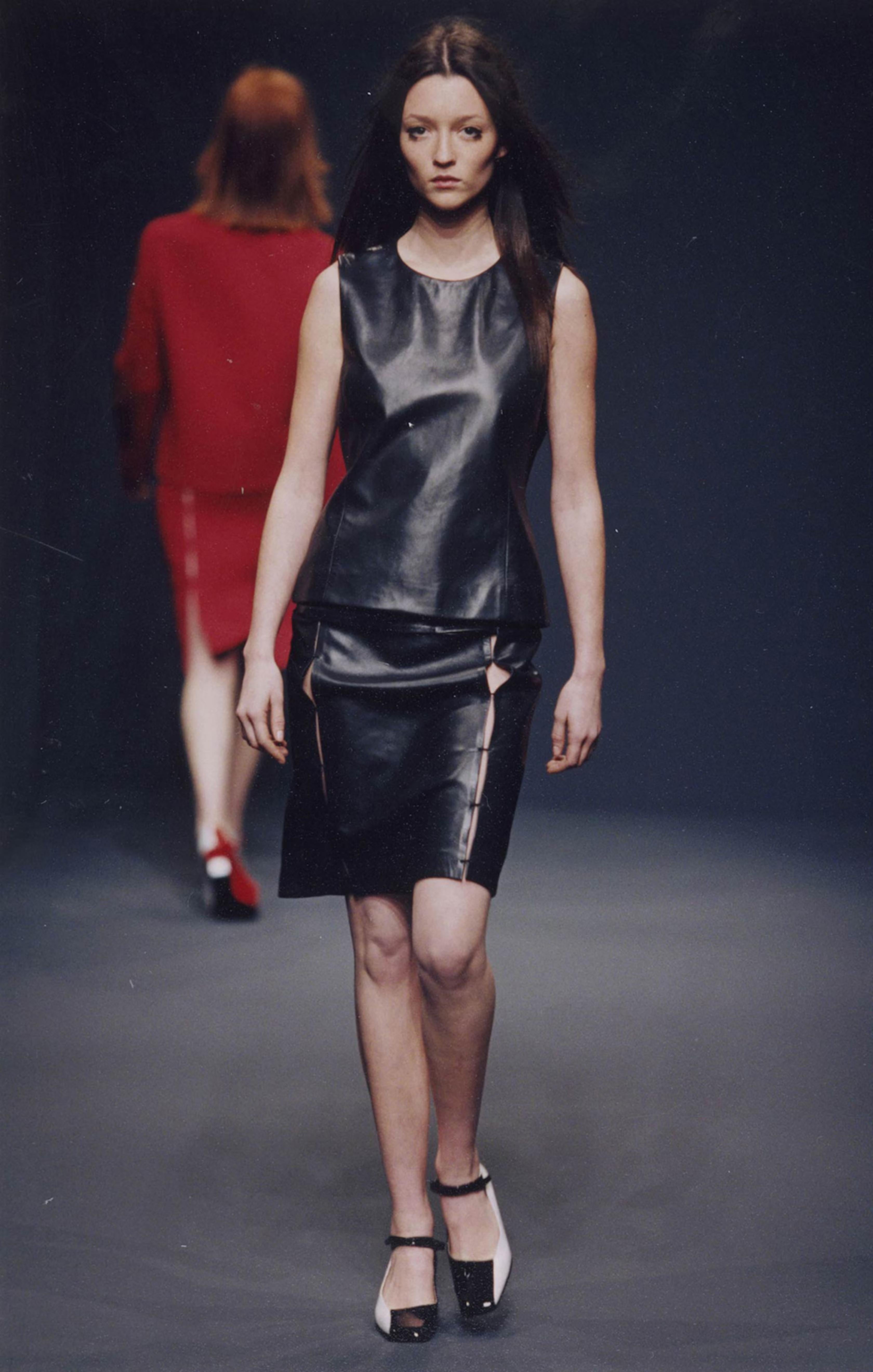 Pezzo raro e da collezione dell'iconica collezione Prada per l'Autunno/Inverno 1998, questo top in pelle nera incarna l'elegante minimalismo e la raffinatezza sottilmente sovversiva che hanno definito la fine degli anni '90 di Prada. Presentato