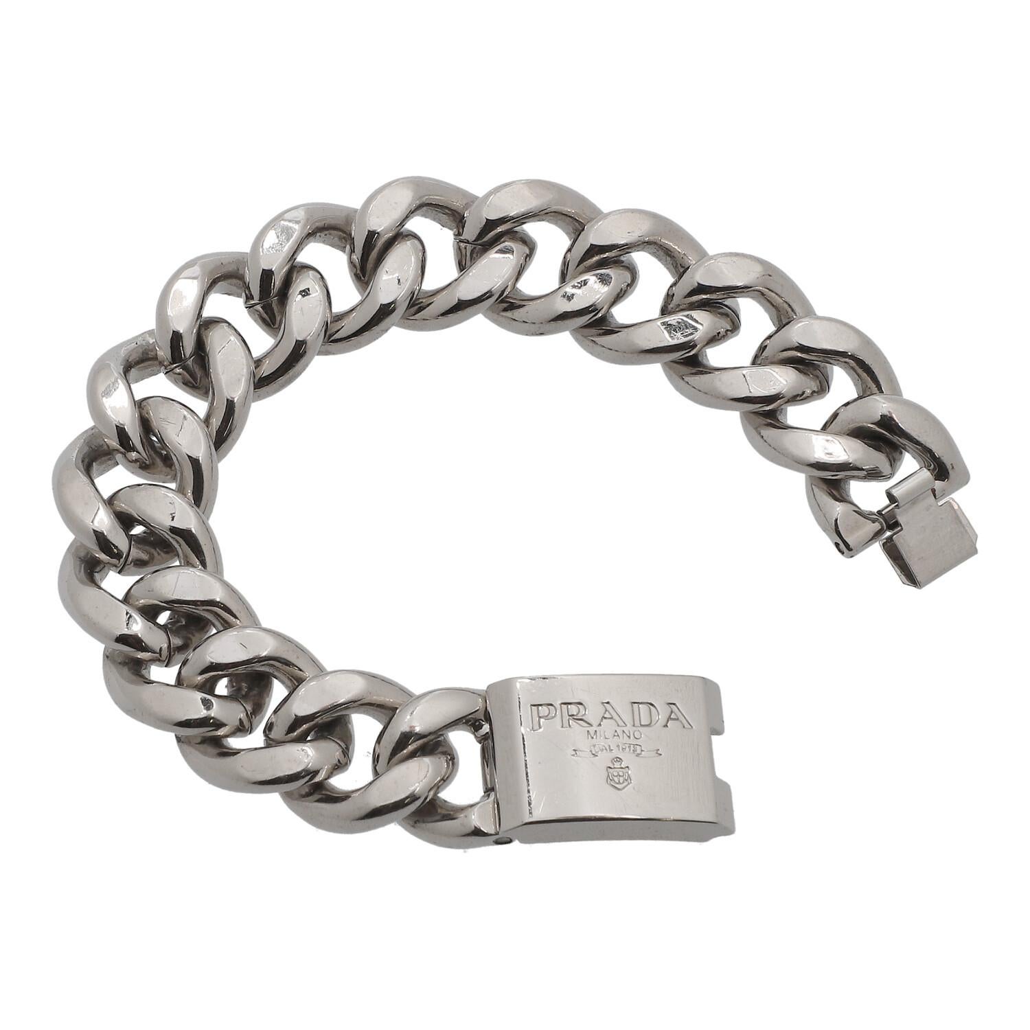 Silver colored curb chain with logo detail on the clasp. Case attached. scratches present. L.: 19 cm.
