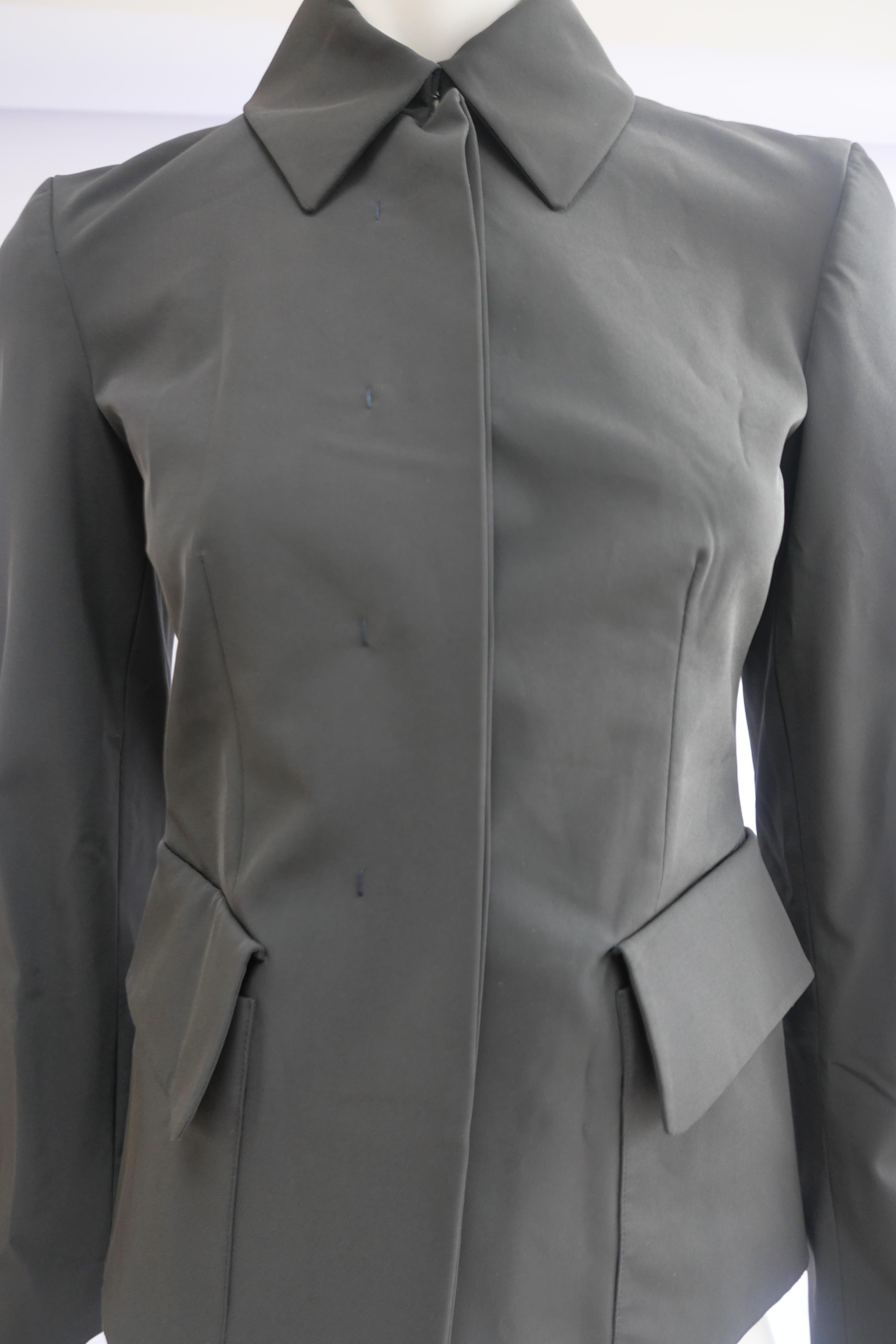 Prada Fitted Jacket 38 Dark Grey 
This piece is a fitted Prada jacket with concealed buttons. The design is modern and minimal in the classic Prada design style. 
Size:	38
Shoulder width: 38 cm 
Width: 40 cm 
Sleeve length: 60 cm 
Length: 56