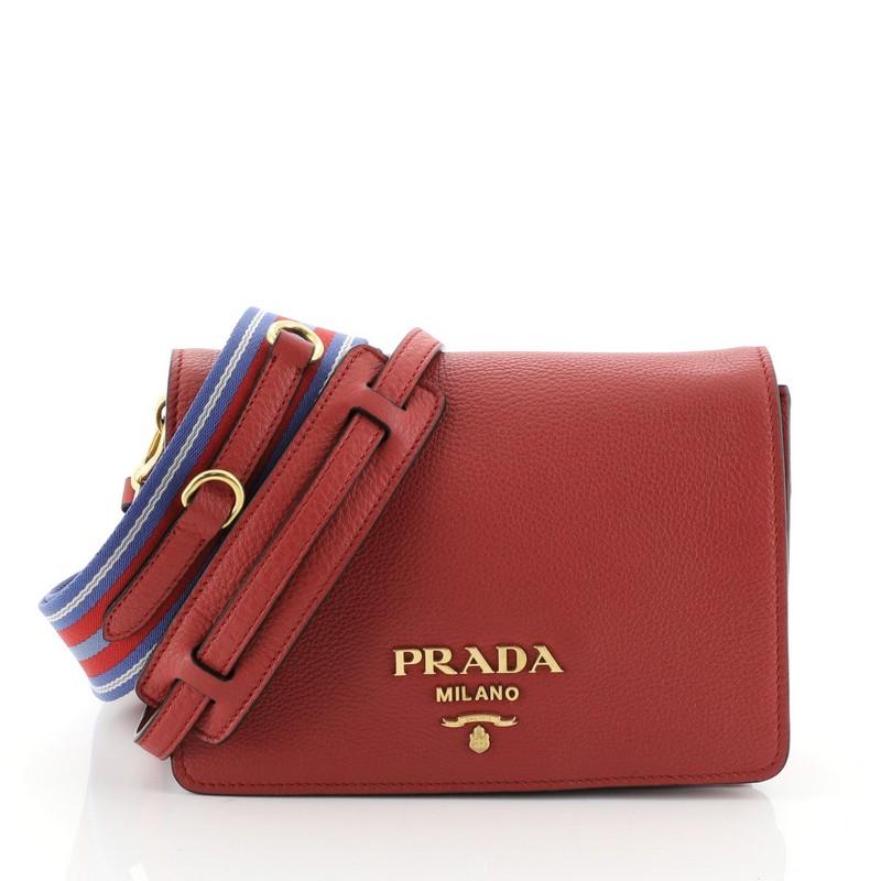 This Prada Flap Crossbody Bag Vitello Daino Small, crafted in red vitello daino leather, features flat shoulder strap, front flap with raised Prada logo, and gold-tone hardware. Its magnetic closure opens to a black fabric interior divided into two