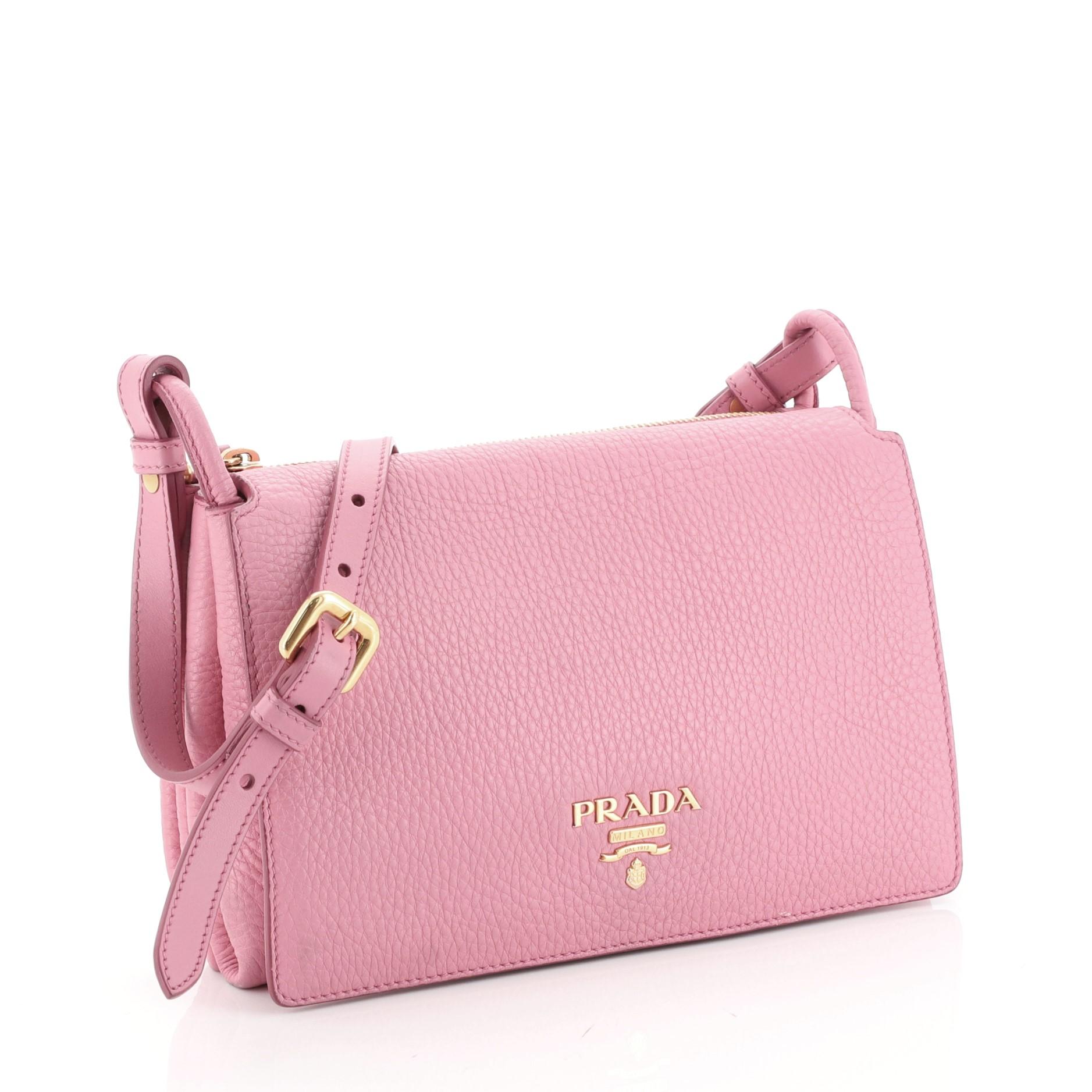 This Prada Flap Crossbody Bag Vitello Daino Small, crafted in pink vitello daino leather, features flat shoulder strap, front flap with raised Prada logo, and gold-tone hardware. Its magnetic closure opens to a pink fabric interior divided into two