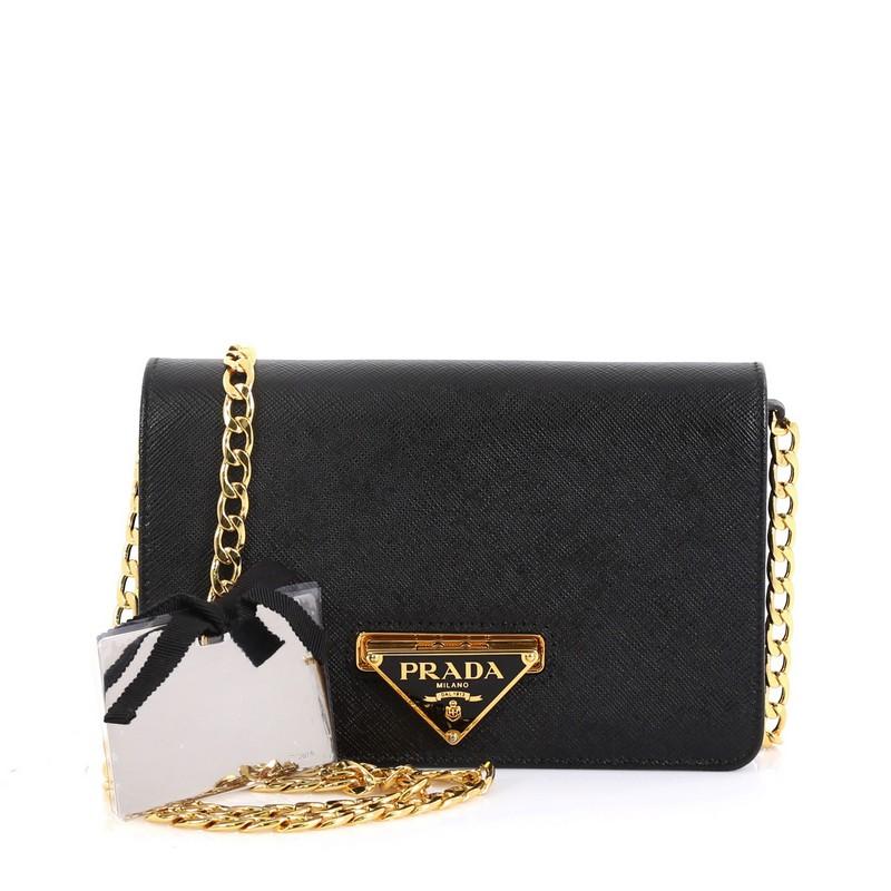 This Prada Flip Lock Wallet on Chain Clutch Saffiano Leather Small, crafted from black saffiano leather, features chain link strap and gold-tone hardware. Its flip lock closure opens to a red leather interior with a middle zip compartment and side