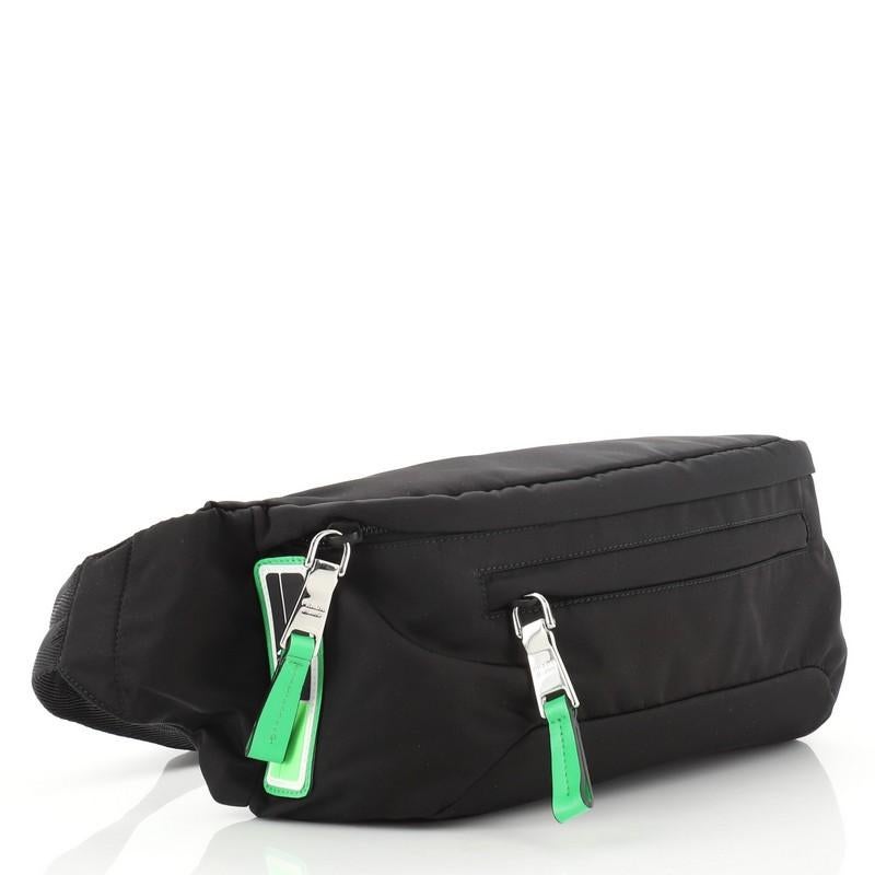 This Prada Fluo Waist Bag Tessuto Medium, crafted in black tessuto, features an adjustable waist strap, two exterior zip pockets, and silver-tone hardware. Its zip closure opens to a green nylon and fabric interior. 

Estimated Retail Price:
