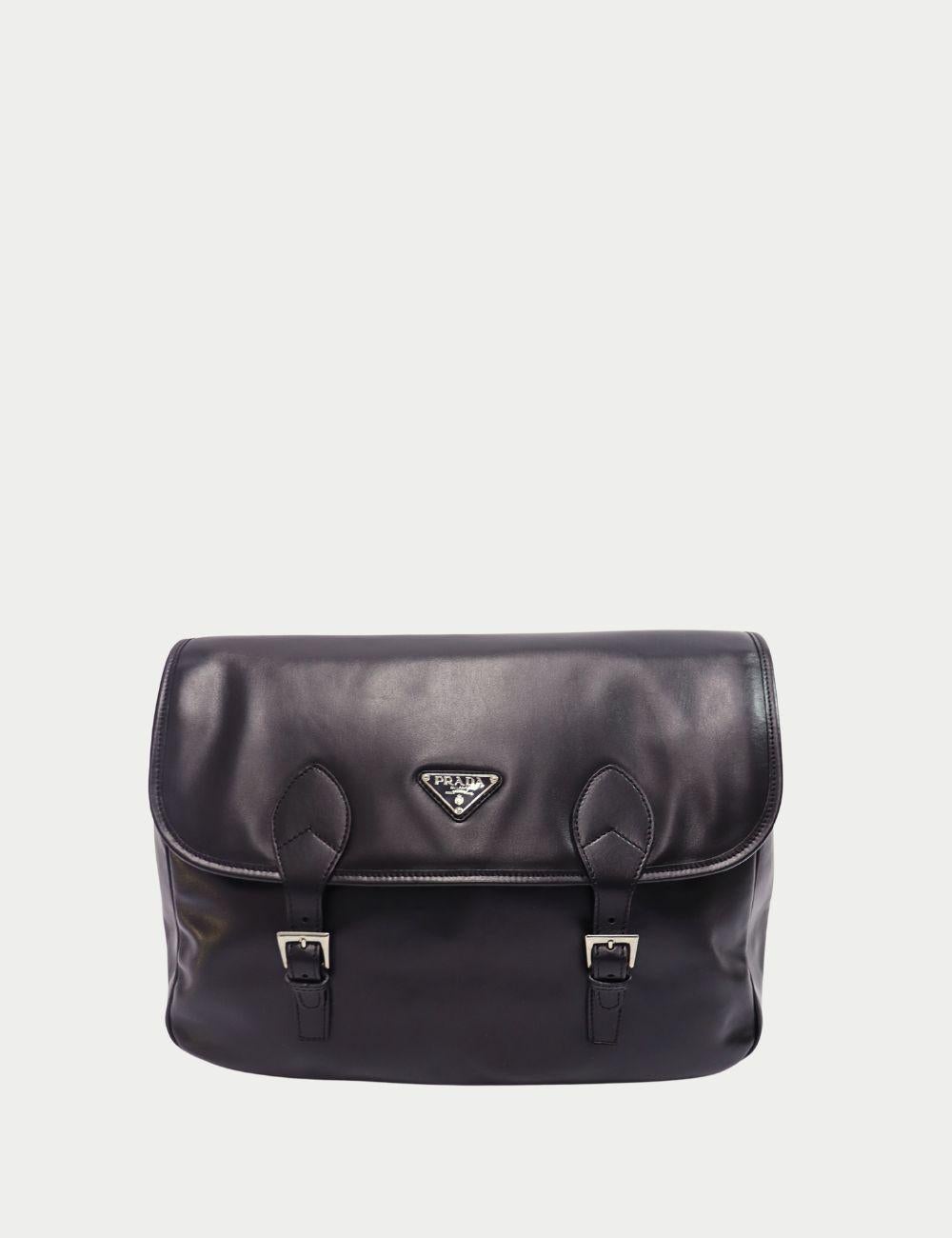 Tragen Sie zeitlose Eleganz mit dieser Prada Kuriertasche aus schwarzem Leder, die mit der für die Marke typischen Liebe zum Detail gefertigt wurde. Sie ist aus Glattleder gefertigt und verfügt über einen Überschlag mit zwei Schnallenriemen,