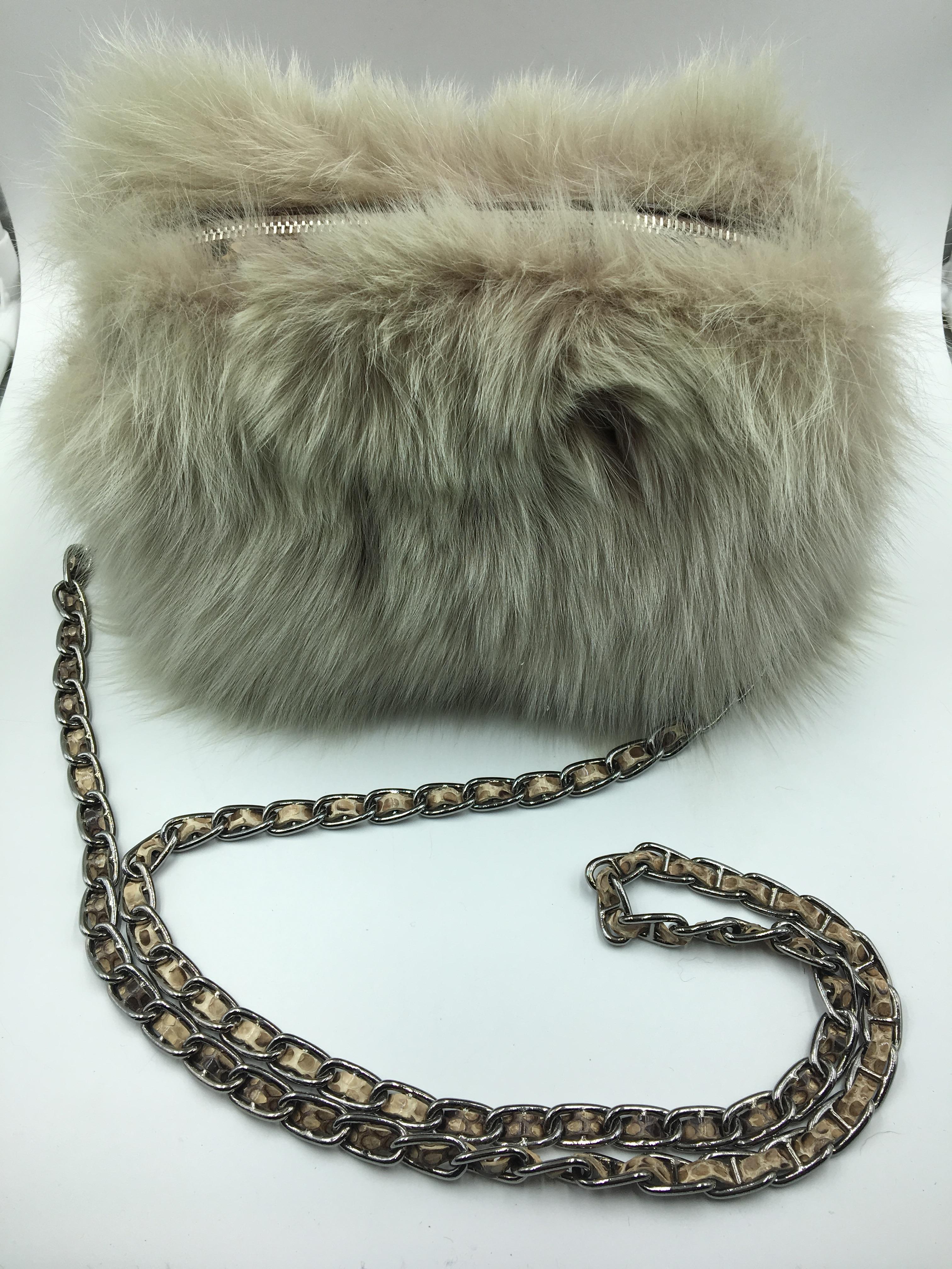 Soft Prada bag with a rounded shape, covered with beige fox fur on the front and back with rigid profiles made of shiny python leather in the same colour as the fur.
This Fox Fur Bag is characterized by metal accessories with palladium finishes,