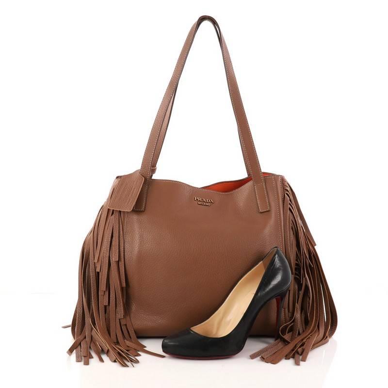This authentic Prada Fringe Tote Cervo Leather Large combines classic and easy style with a chic twist perfect for daily excursions. Crafted from brown cervo leather, this 70s-inspired stylish tote features cascading fringe details at its sides,