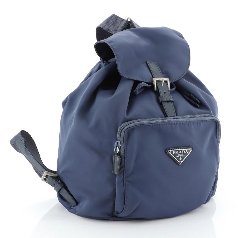 This Prada Front Pocket Backpack Tessuto Small, crafted in blue tessuto fabric, features backpack shoulder straps, exterior front zip pocket, and silver-tone hardware. Its buckle closure opens to a blue fabric interior with zip and slip pockets.