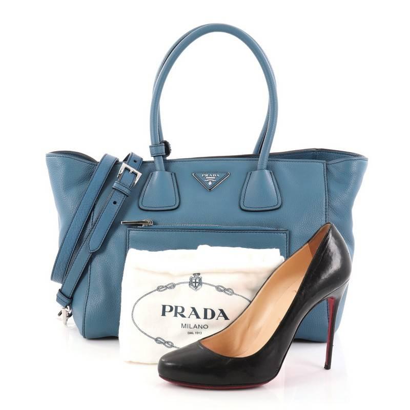This authentic Prada Front Pocket Wing Convertible Tote Vitello Daino exudes a stylish and industrial design made for everyday excursions. Crafted from blue vitello daino leather, this tote features dual-rolled leather handles, exterior front zip