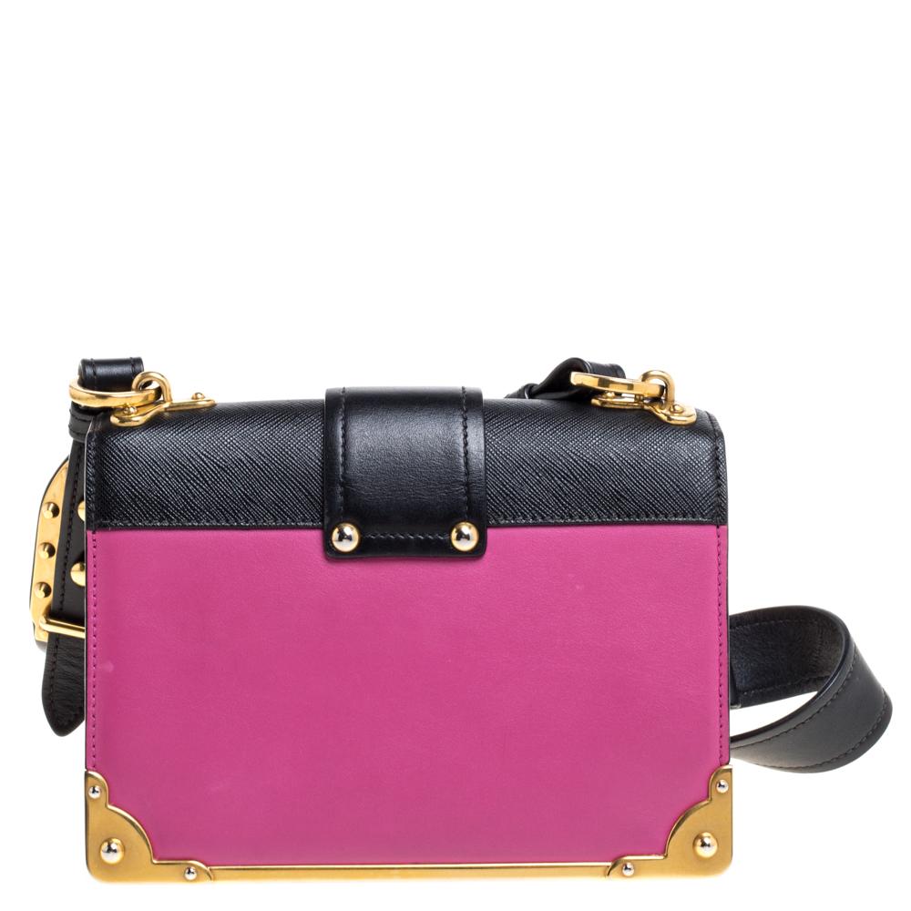 This gorgeous bag by Prada imparts a regal appeal and has a structured silhouette. Crafted from leather in a combination of fuschia and black hues, it exudes impeccable Italian craftsmanship. The creation is adorned with gold-tone hardware and a