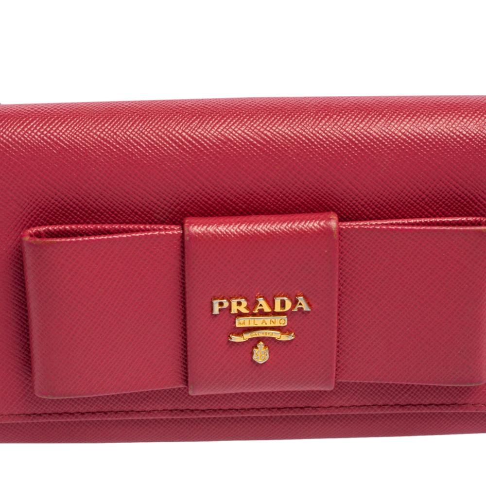 This designer continental wallet by Prada has a beautiful look. Crafted from Saffiano leather, it comes in a fuchsia shade. It has a front flap with a bow detail that adds charm and its lined interior has enough space for all your essentials.

