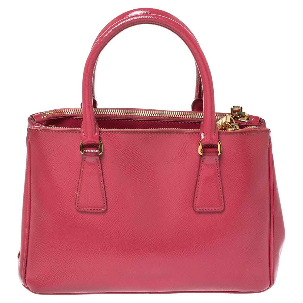 Feminine in shape and grand on design, this Double Zip tote by Prada will be a loved addition to your closet. It has been crafted from Saffiano patent leather and styled minimally with gold-tone hardware. It comes with two top handles, two zip