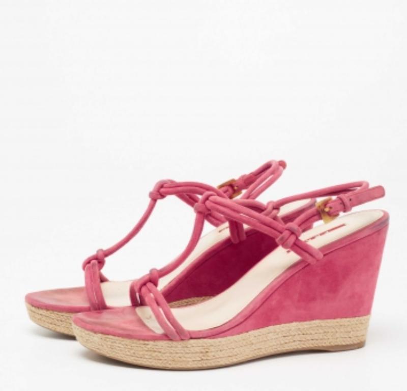Add a dash of pink to your attire with these sandals from the House of Prada. They are created using fuschia pink suede and showcase espadrille wedge heels, open toes, and buckled closure. They flaunt gold-tone fittings. Look chic as you walk in