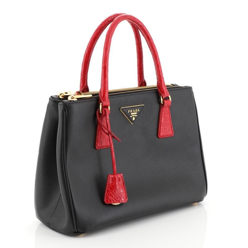 This Prada Galleria Double Zip Tote Saffiano Leather with Crocodile Small, crafted from black saffiano leather with genuine crocodile, features side snap buttons, raised Prada logo plate, dual rolled handles, and gold-tone hardware. It opens to a