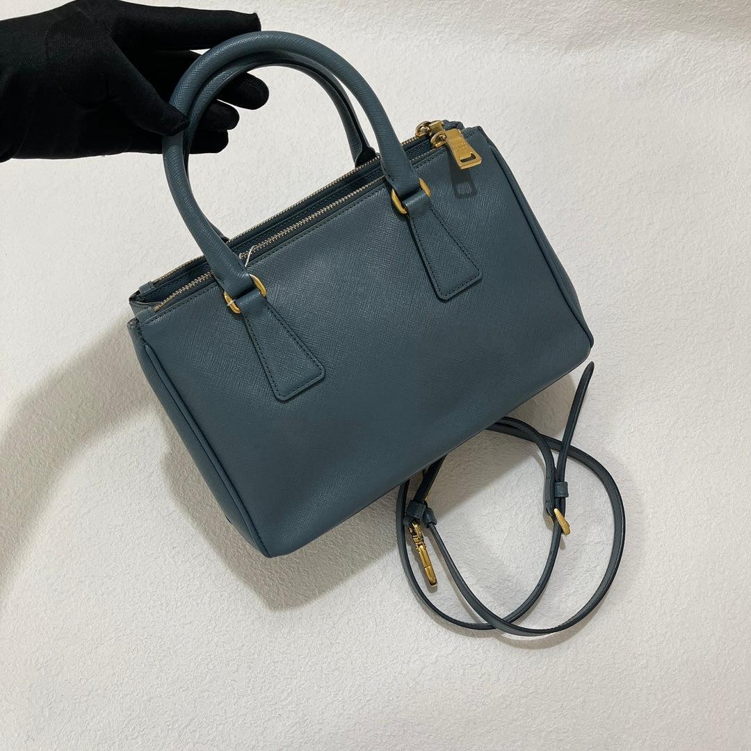 Prada Galleria Saffiano Leather Mini Grey Blue Handbag with Strap
  These are professional photos of the actual bag offered by Luxbags.
  CONDITION: VERY GOOD
  Light cracks on the two side buttons
  DETAILS
  
  Size: MiniDimensions: Height 14cm,