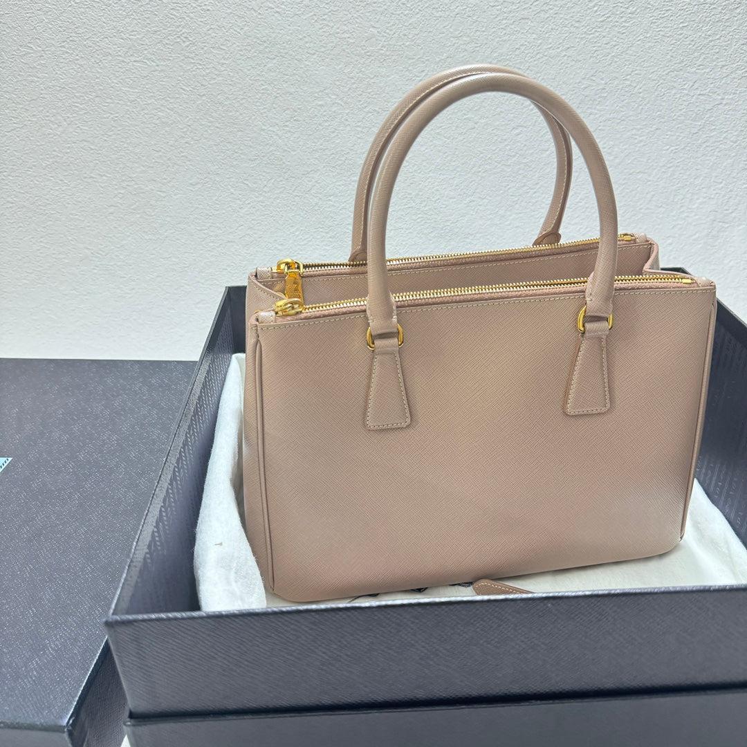 Prada Galleria Saffiano Leather Small Light Pink Handbag with Strap
 These are professional photos of the actual bag.
 Condition: NEVER WORN
 DETAILS
 
 Prada
 Galleria
 Material: Black saffiano calfskin leather
 
 Color: Light pink / Pale pink
