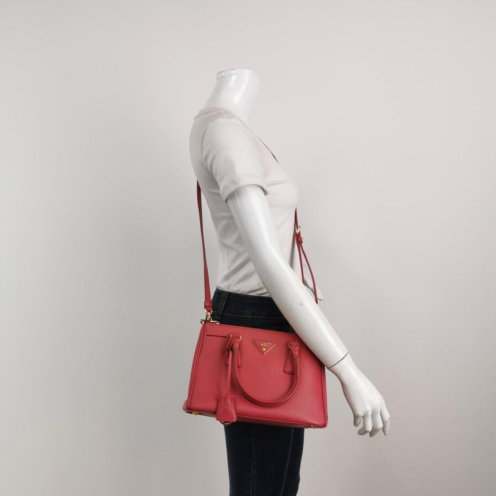 Prada Galleria Saffiano Leather Small Pink Handbag with Strap These are professional photos of the actual bag offered by Luxbags. Size: SmallDimensions: Width 26cm; Height: 16cm, Depth: 10.5cmColor: PinkHardware Color: GoldAccessory: StrapCondition: