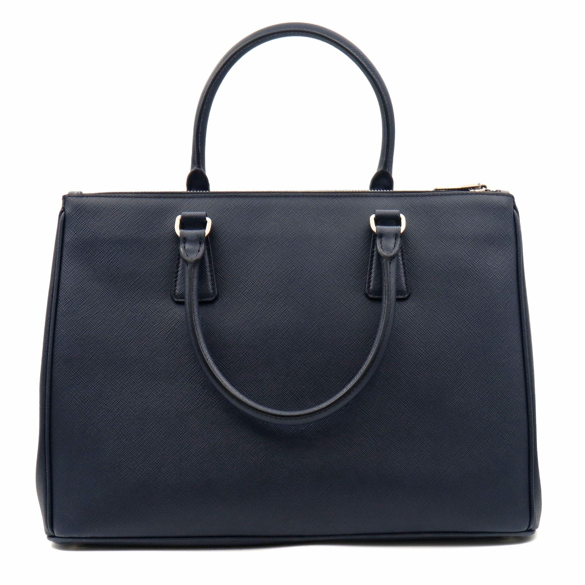 Prada Galleria Saffiano Lux Medium size bag in dark navy blue (Baltico). Model BA274 NZV F0DMH0. This bag prominently showcases a double leather handle and detachable/adjustable shoulder strap. Additional appealing features include silver toned
