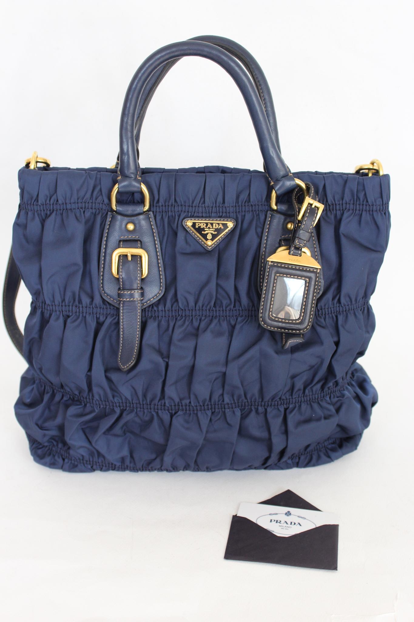 Prada Gaufre bag in Baltic blue color 2000s. Bag made of fine multi-layered pleated nylon fabric with gold-colored details. The bag can be carried by hand using the leather handles or over the shoulder, the latter being adjustable. Clip button