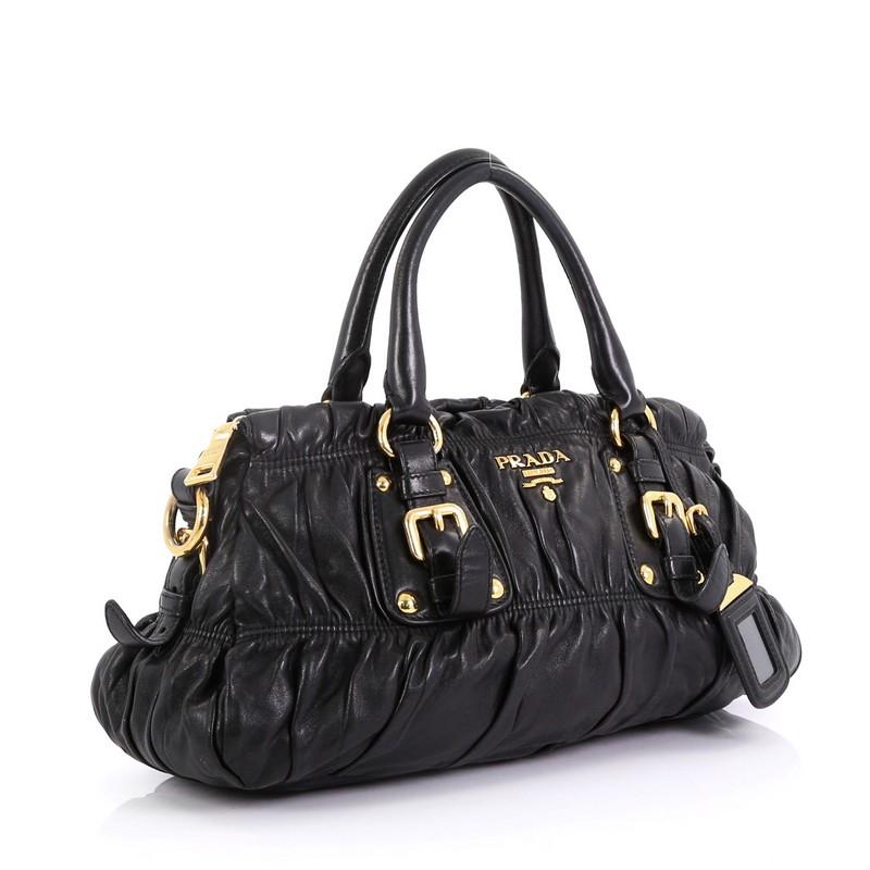 This Prada Gaufre Convertible Satchel Nappa Leather Medium, crafted in black nappa leather, features dual rolled handles, belted sides, and gold-tone hardware. Its zip closure opens to black fabric interior with side zip and slip pockets.