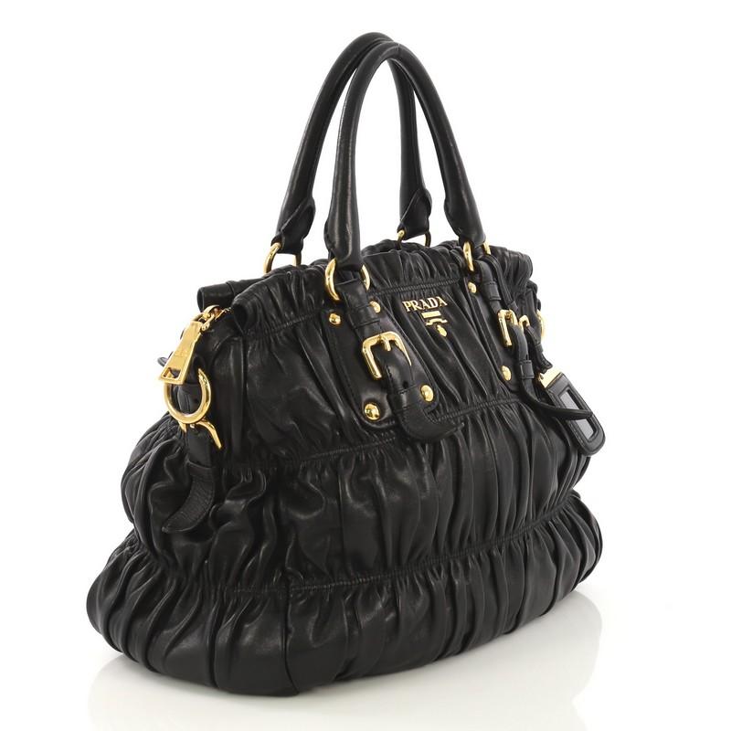 This Prada Gaufre Convertible Tote Nappa Leather Medium, crafted in black nappa leather, features dual rolled handles, Prada logo at the center, and gold-tone hardware. Its zip closure opens to a black fabric interior with side zip and slip