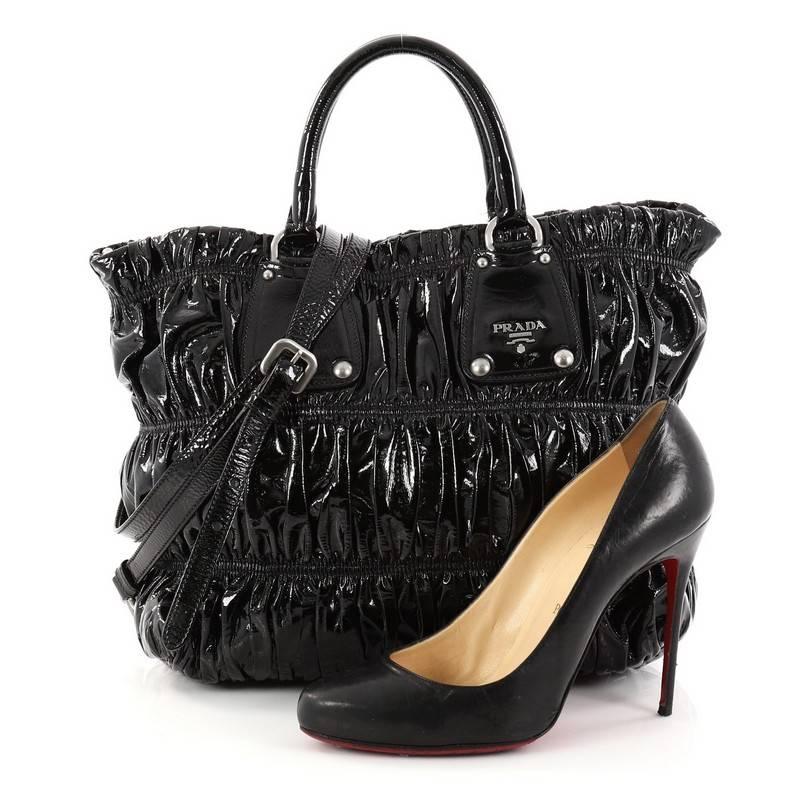 This authentic Prada Gaufre Convertible Tote Patent Medium is a beautifully and intricately crafted bag perfect for everyday use. Constructed in black patent leather, this bag features dual-rolled handles with belt and buckle detailing, trademark