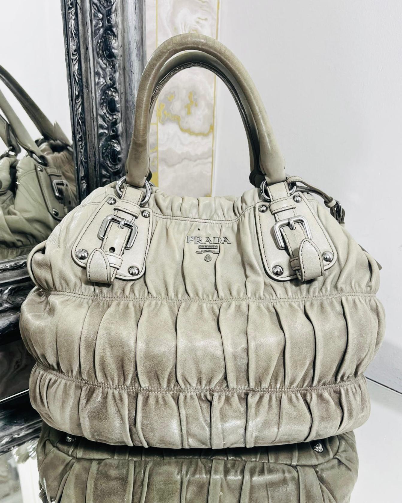 Prada Gaufre Leather Tote Bag

Dark dusty beige bag designed with silver 'Prada' logo to the front.

Detailed with soft ruched leather and buckles detailing to the rolled dual top handle.

Featuring leather tag attached and snap closure leading to