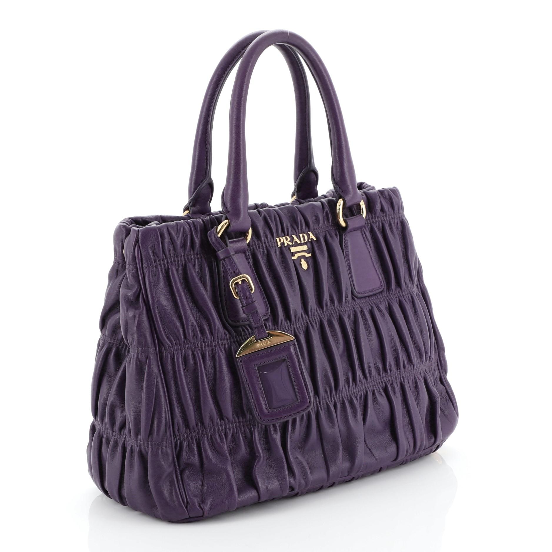 This Prada Gaufre Tote Nappa Leather Small, crafted in purple nappa leather, features dual rolled handles and gold-tone hardware. Its zip closure opens to a purple fabric interior with side zip and slip pockets.

Condition: Great. Creasing near