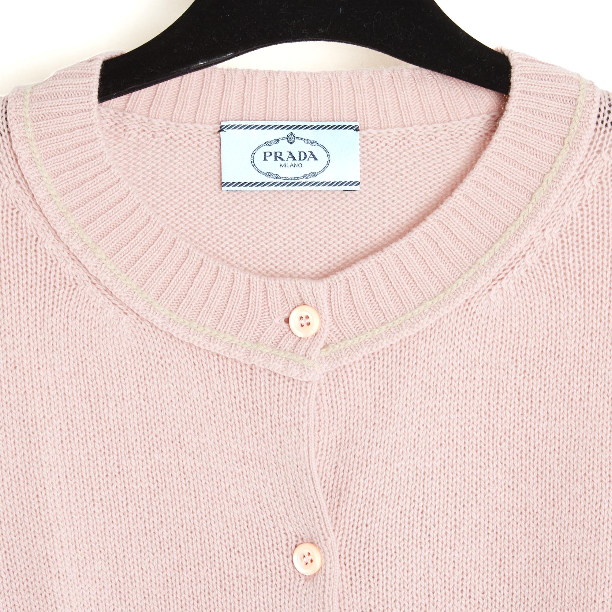 Cardigan di Prada in lana (70%) e cashmere rosa pallido, collo rotondo chiuso da 7 bottoni di perle rosa, maniche lunghe, finiture a coste sul collo, sui polsini e sul fondo del cardigan. Taglia IT44 o FR40 o UK12 e US10: spalle 39 cm, petto 47 cm,