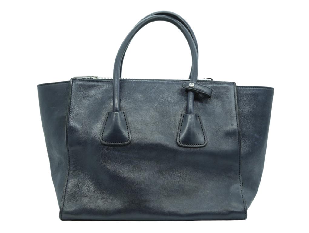Gorgeous bag from Prada. This stylish tote is beautifully crafted of luxurious glazed calfskin leather in powder beige. The bag features rolled leather top handles and an optional leather shoulder strap with silver clasps. The bag features a wide