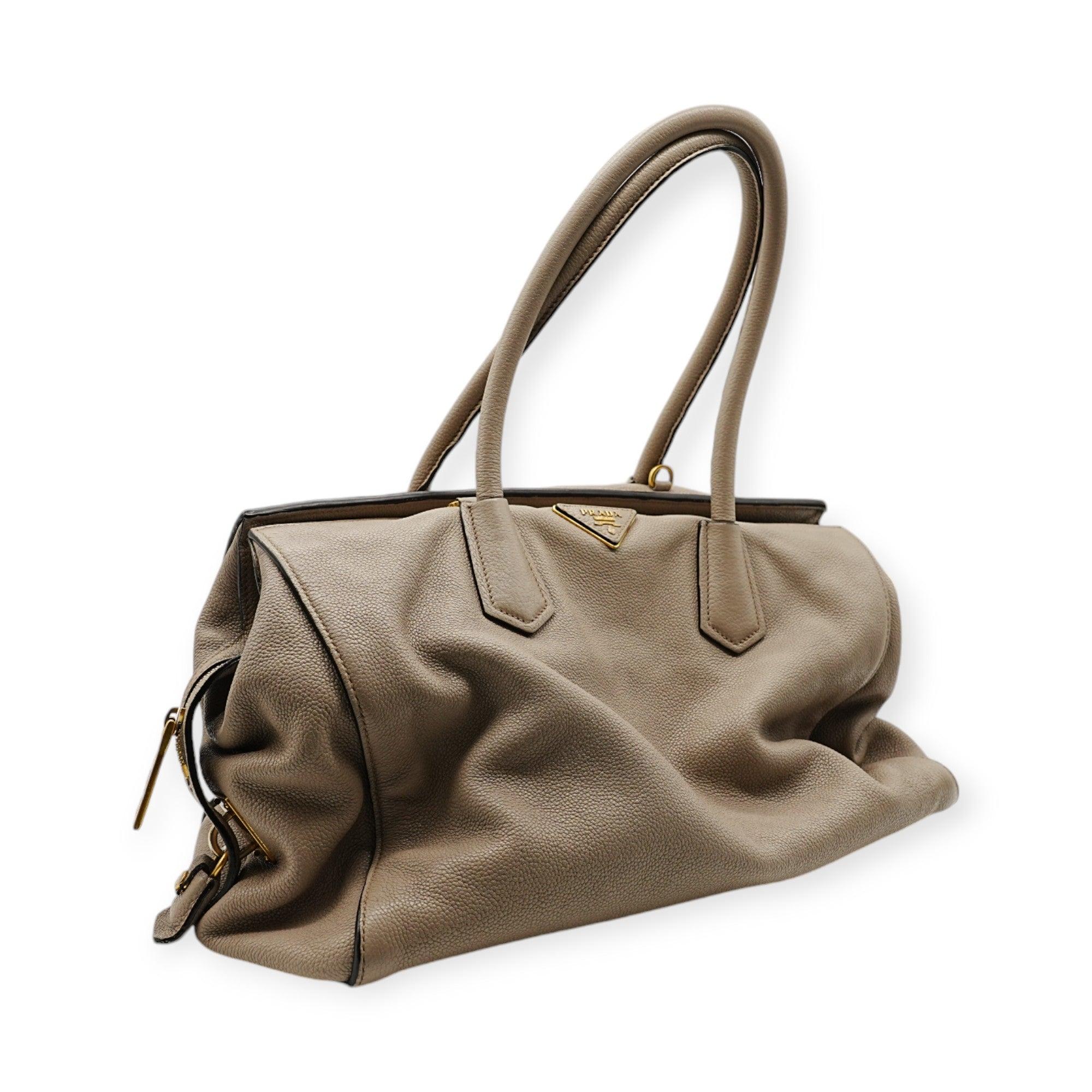 The Prada Glace Grey Shopping Bag features a spacious design, perfect for carrying all your essentials. Its sleek grey finish and minimalist style make it an elegant yet practical choice for everyday use. 
 Height:25;Length:38;Width:15  Material: