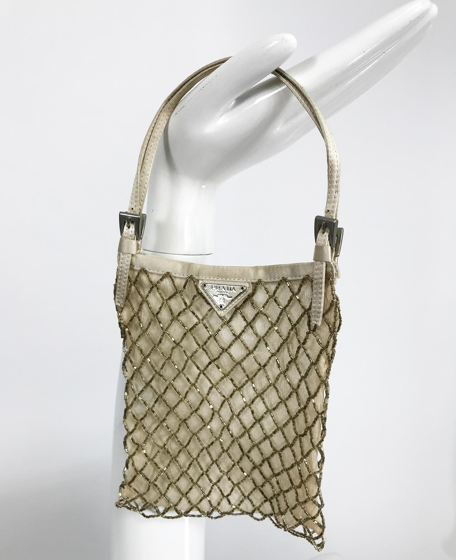 Prada gold beaded, silk chiffon lined, mini evening bag. This sweet bag has double off white sating handles with silver hardware. The bag itself is rectangle with a metal Prada logo at the top front. Cris-cross gold glass tube beads form a diamond