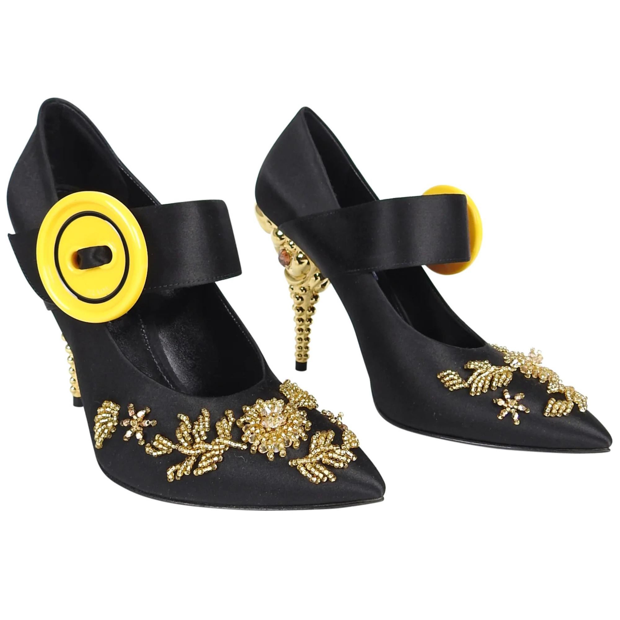 The pumps are constructed of black satin and embellished with gold beads with a bright yellow button. The pumps feature black satin, gold jewelled heel, yellow button at strap, and a sculpted gold metal heel. Pointed toe with beaded details. 110 mm