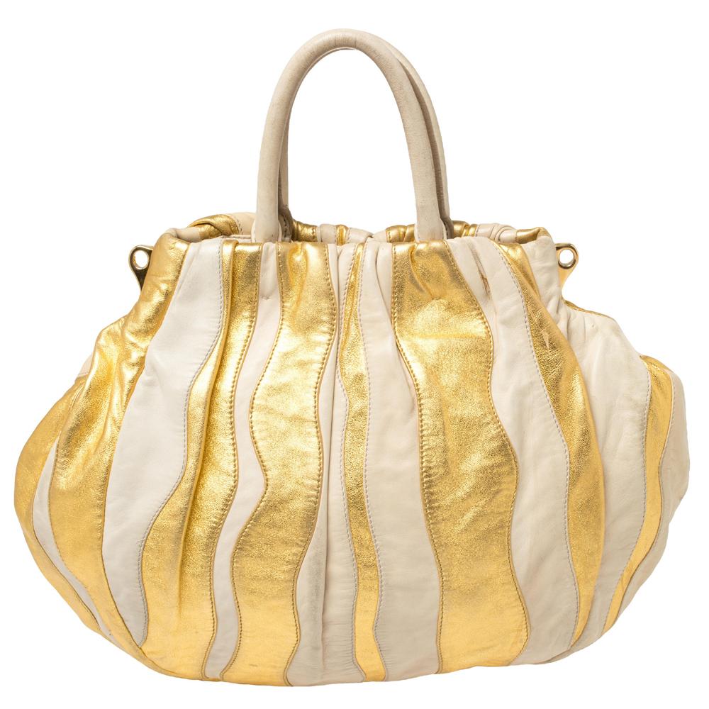 This Prada hobo for women comes fashioned with quality leather. It has an exterior laid with gold & beige panels thus forming wavy stripes. The bag is lined with leather and held by a single handle. The bag is finished with gold-tone hardware and