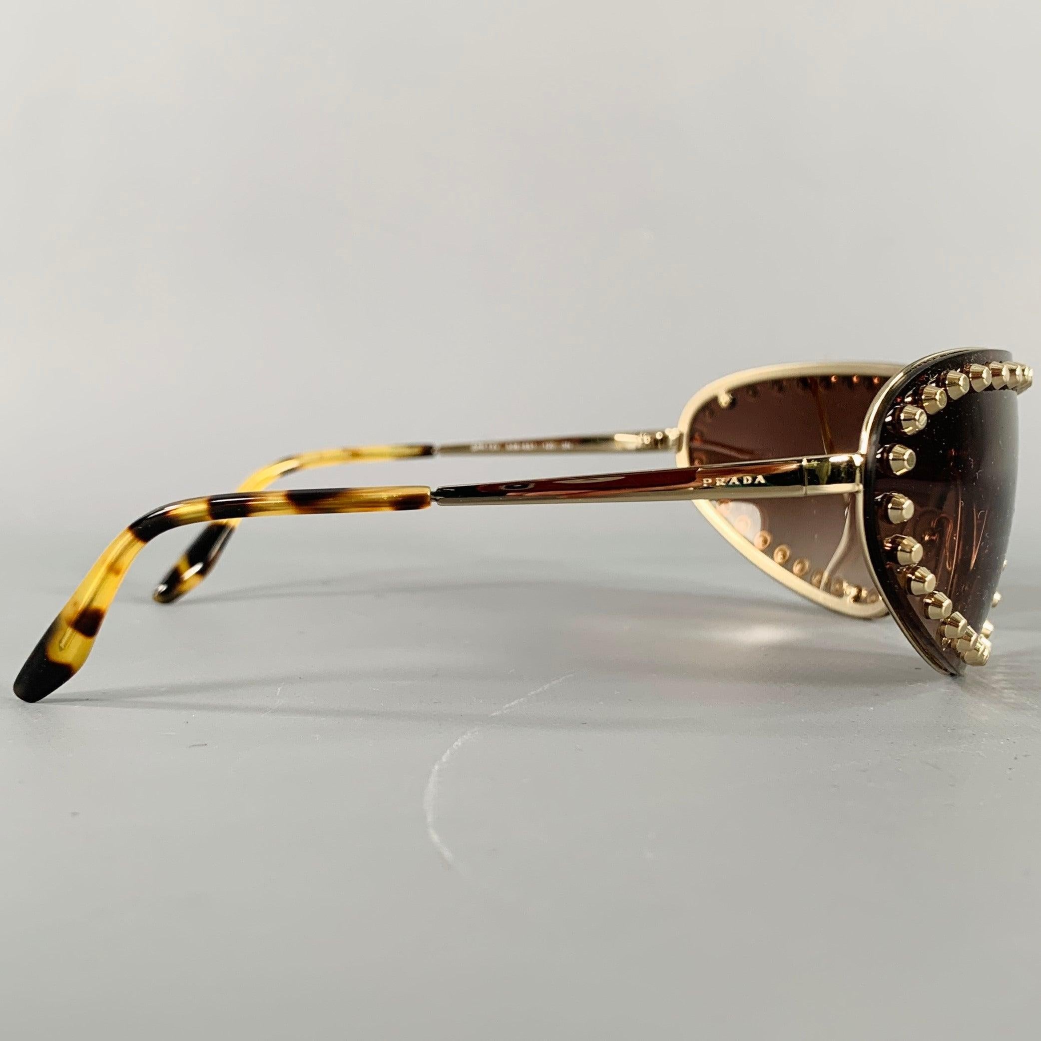 PRADA sunglasses
in a gold tone metal featuring a studded border design, wrap around style, and brown tinted lenses. Comes with case.Good Pre-Owned Condition. 

Marked:   SPR 73V 508-6S1 120 3N 

Measurements: 
  Frame Width: 14.5 cm.Frame Height: