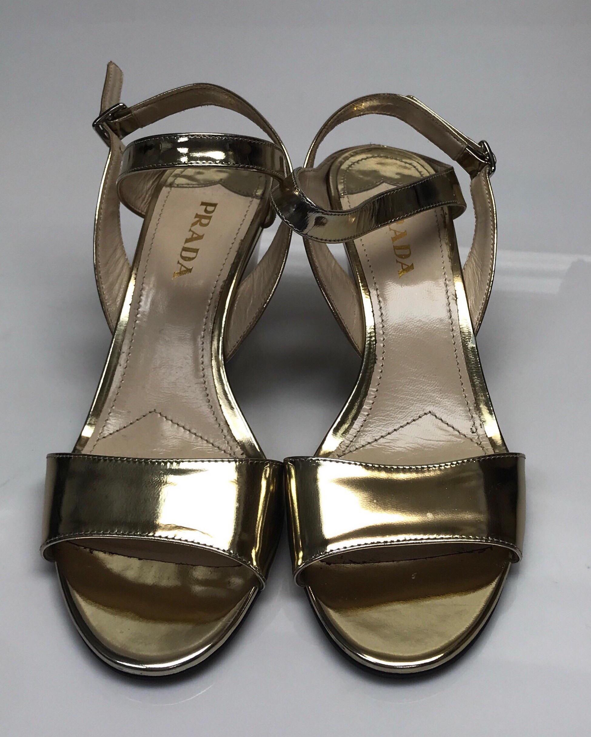 PRADA Gold Patent Leather Ankle Strap Wedge - 38. This beautiful Prada wedge is in good condition. There is minimal sign of use, including small smudges on the heel and wrinkling of the strap. This wedge is made of gold patent leather and has an