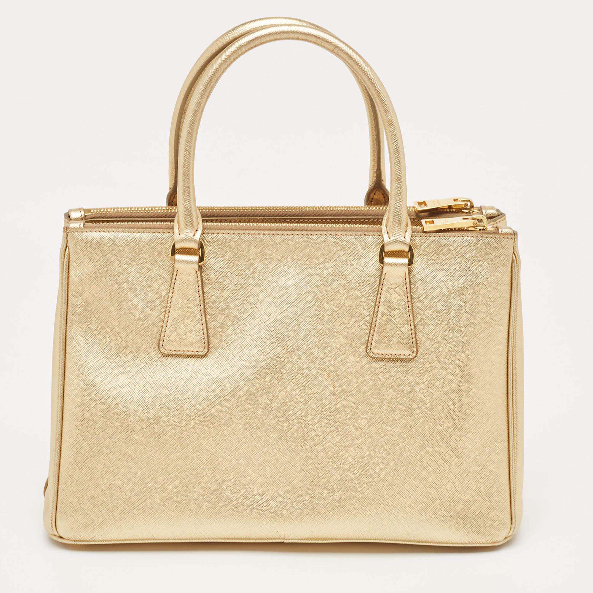 Diese goldene Tasche von Prada ist ein Beispiel für die feinen Designs der Marke, die durch ihre geschickte Verarbeitung einen klassischen Charme versprühen. Es handelt sich um eine funktionelle Kreation mit einer gehobenen Ausstrahlung.

Enthält: